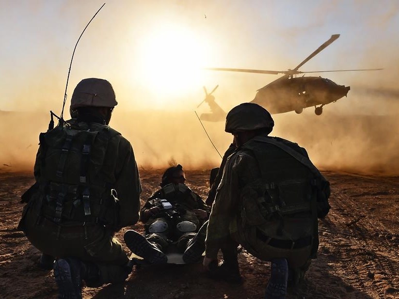 Sayeret Givati soldiers tending a wounded comrade at dusk as a helicopter lands